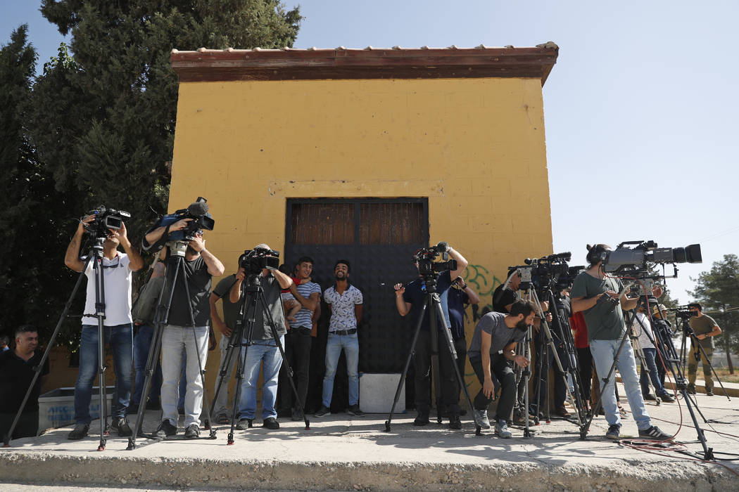 Residents look on as members of the media work at the border between Turkey and Syria, in Akcak ...