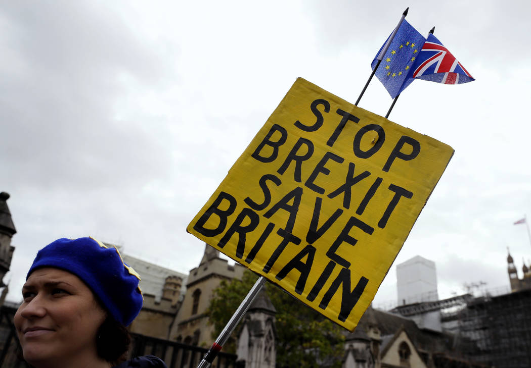 An anti-Brexit campaigner holds a banner near Parliament in London, Tuesday, Oct. 8, 2019. The ...