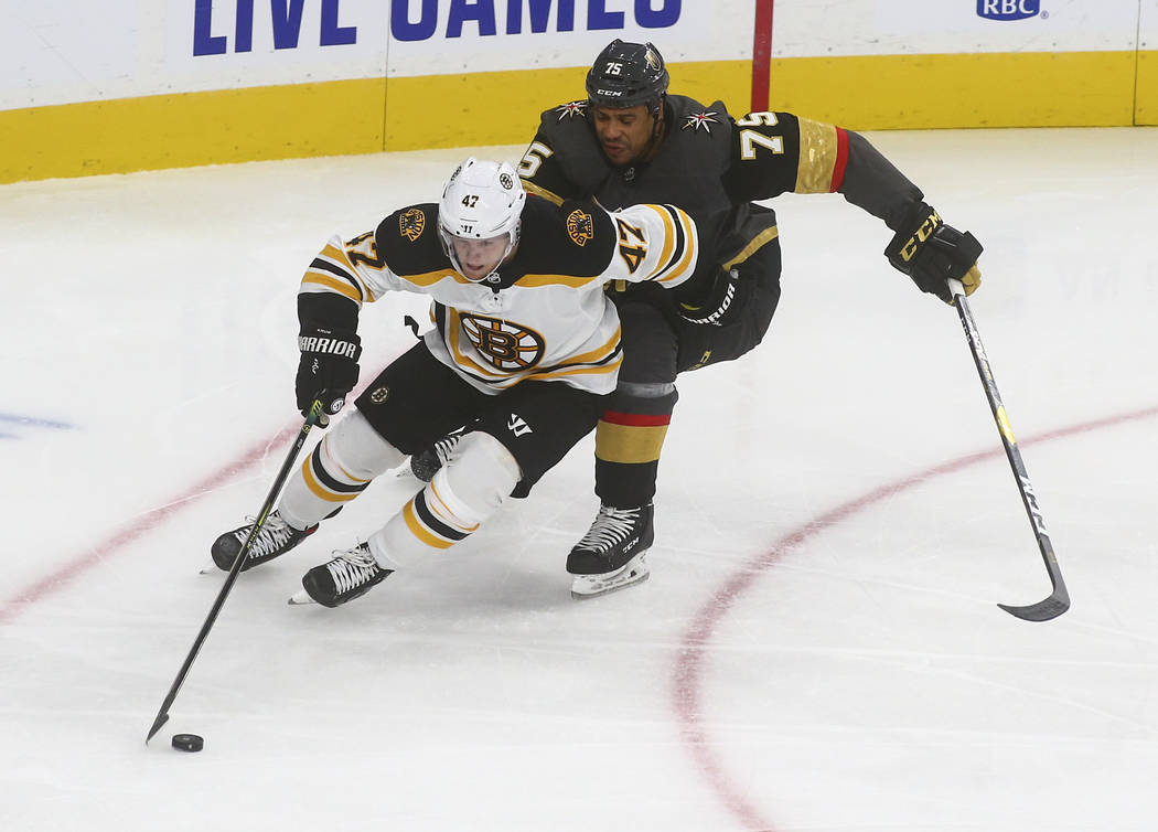 Boston Bruins' Torey Krug (47) skates with the puck under pressure from Golden Knights' Ryan Re ...