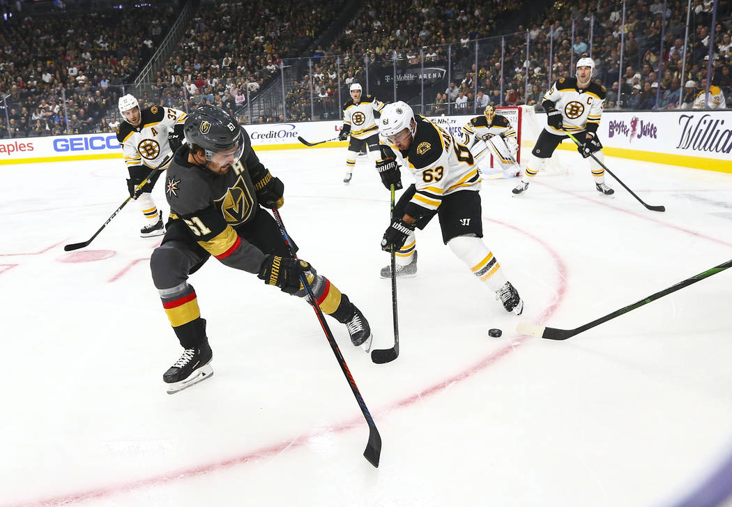 Golden Knights' Mark Stone (61) and Boston Bruins' Brad Marchand (63) battle for control of the ...