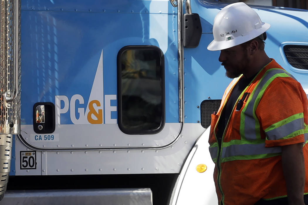 In this Aug. 15, 2019, file photo, a Pacific Gas & Electric worker walks in front of a truck in ...
