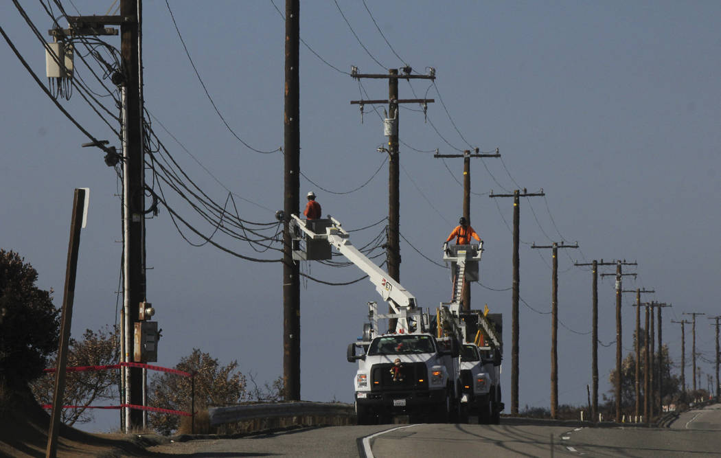 FILE- In this Nov. 25, 2018 file photo utility crews repair overhead lines Sunday, , along Paci ...