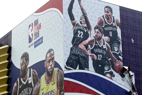 A worker takes down a billboard advertising an NBA preseason basketball game on Thursday betwee ...