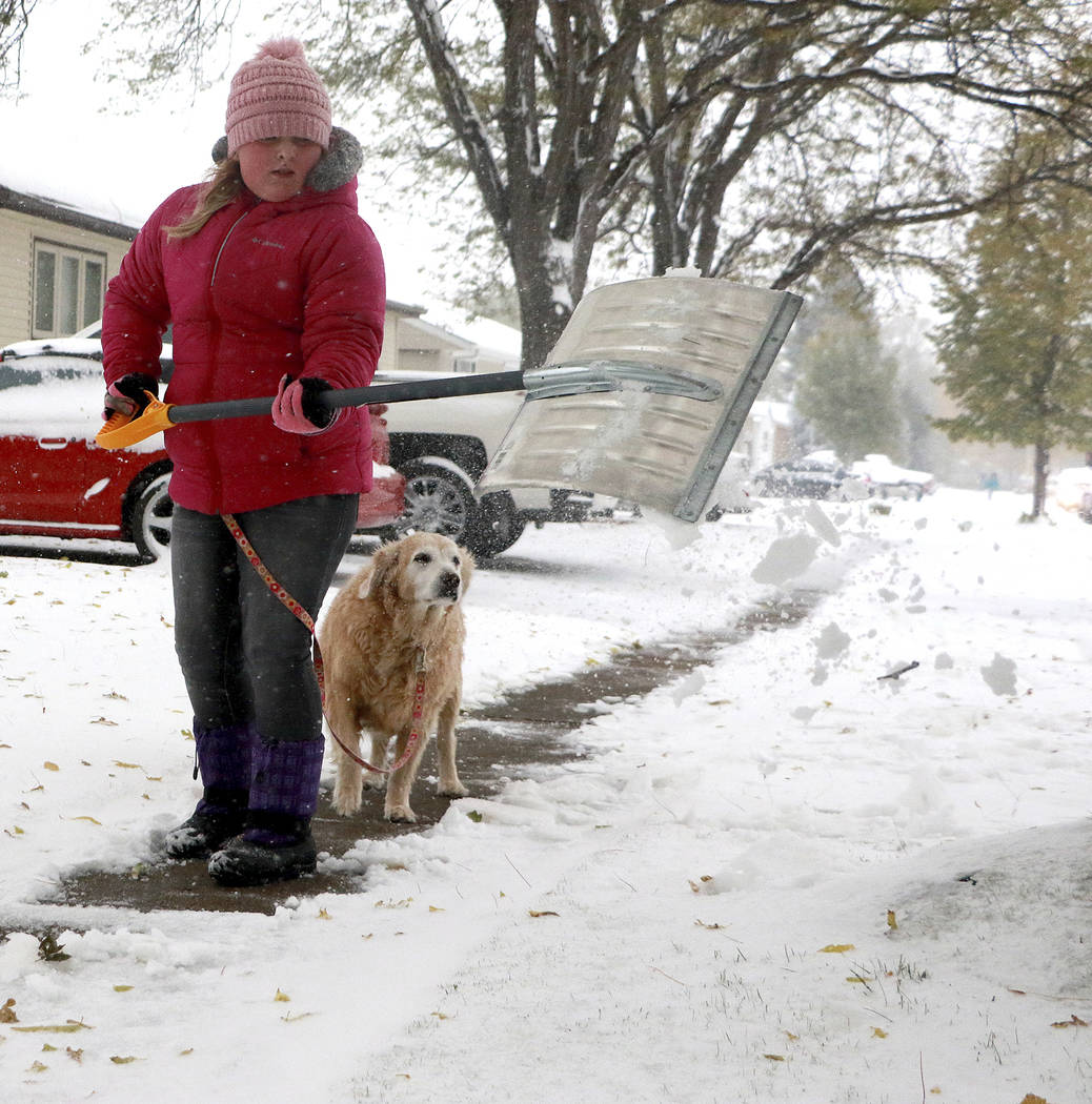 Gianni Green shovels snow off her neighbor's sidewalk along Avenue K in Scottsbluff, Neb., befo ...