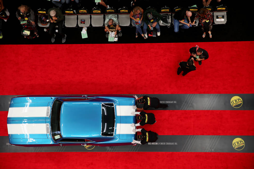 Workers push a car on the auction block during Mecum Las Vegas auction at the Las Vegas Convent ...