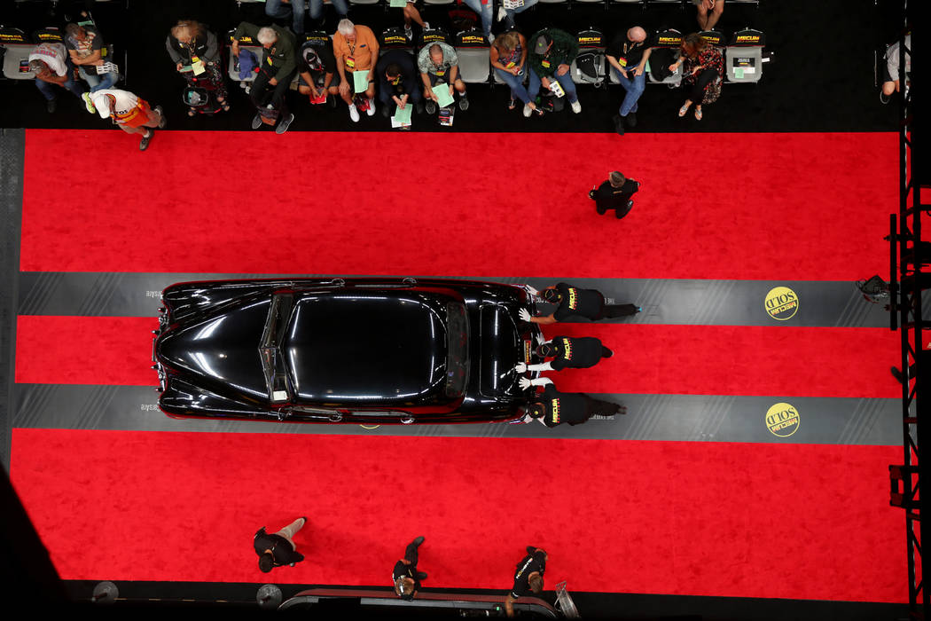 Workers push a car on the auction block during Mecum Las Vegas auction at the Las Vegas Convent ...