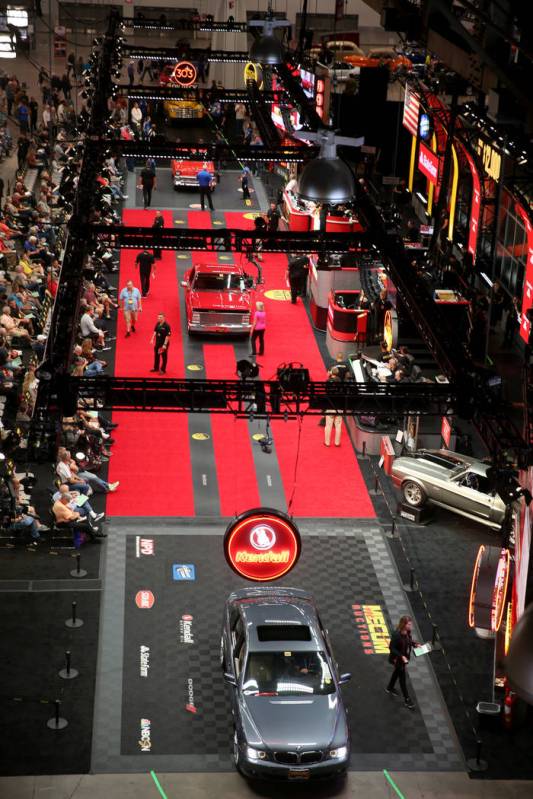Workers push cars on the auction block during Mecum Las Vegas auction at the Las Vegas Conventi ...