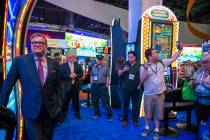Famed gameshow host Drew Carey stands next to one of the IGT Price is Right slot games as a fan ...