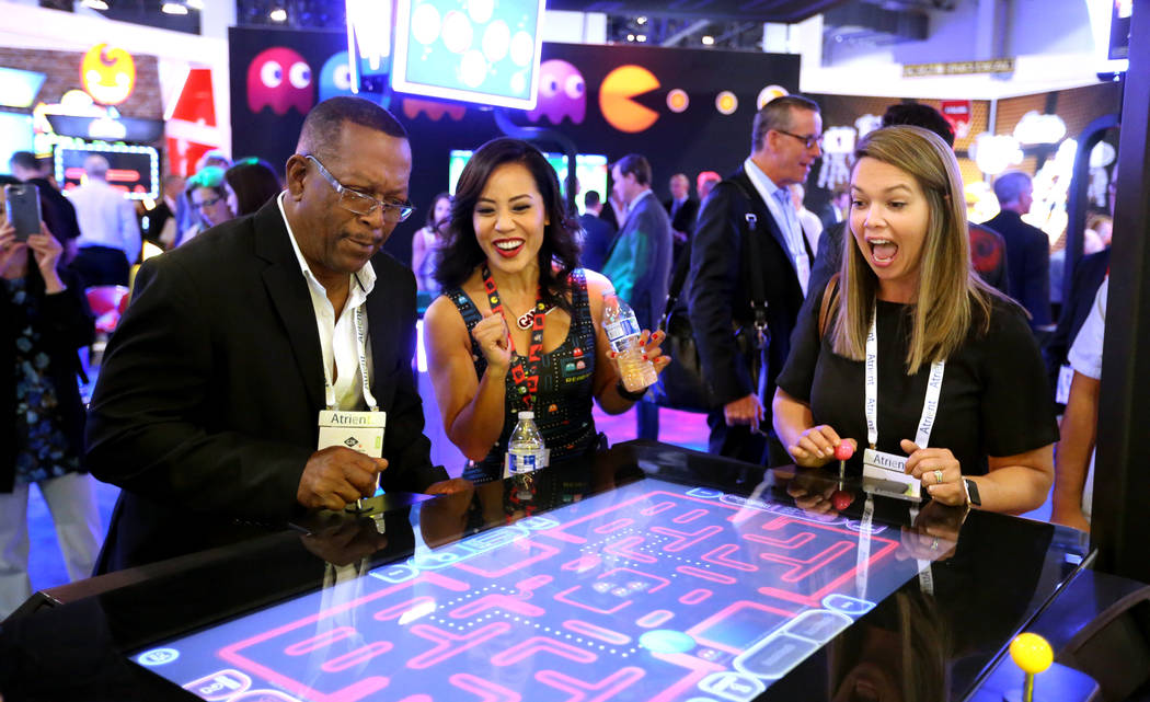 Nikki Tuazon in the Gamblit Gaming booth, center, helps Vernon Finch, a commission member with ...