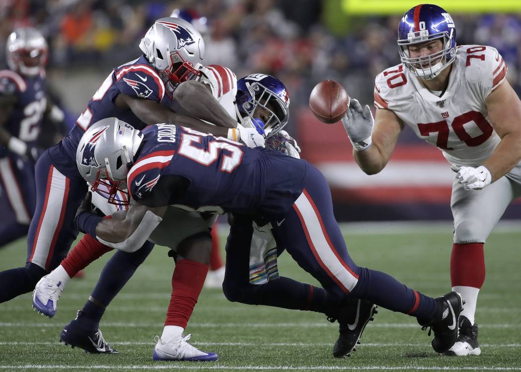 New England Patriots linebacker Jamie Collins, front, forces a fumble as he tackles New York Gi ...