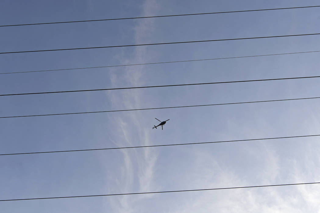 A helicopter hovers above large electrical towers while inspecting the lines in Orinda, Calif., ...