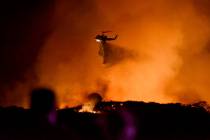 A helicopter drops water on a brushfire in the Santa Monica Mountains in Newbury Park, Calif., ...