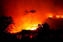 Water is dropped on a large brush fire Friday, Oct. 11, 2019, in Sylmar, Calif. (AP Photo/David ...