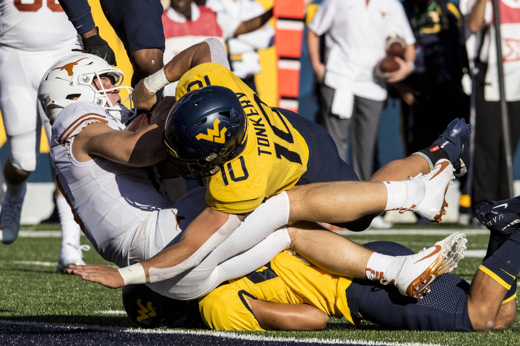 West Virginia linebacker Dylan Tonkery (10) tackles Texas quarterback Sam Ehlinger, left, who c ...