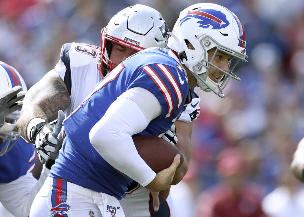 Buffalo Bills quarterback Josh Allen tries to break free from the grasp of of New England Patri ...