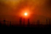 Smoke from the Saddleridge Fire hangs above power lines as the sun rises in Newhall, Calif., on ...