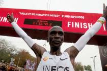 Marathon runner Eliud Kipchoge from Kenya celebrates under the clock after crossing the finish ...