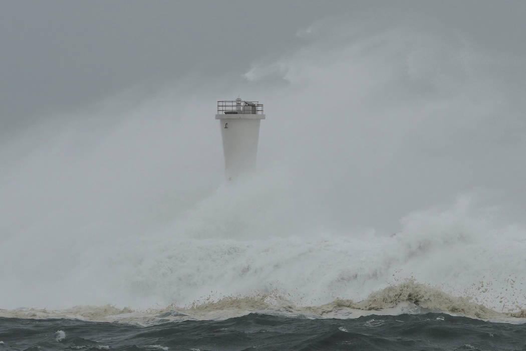 Surging waves hit against the breakwater and a lighthouse as Typhoon Hagibis approaches at a po ...