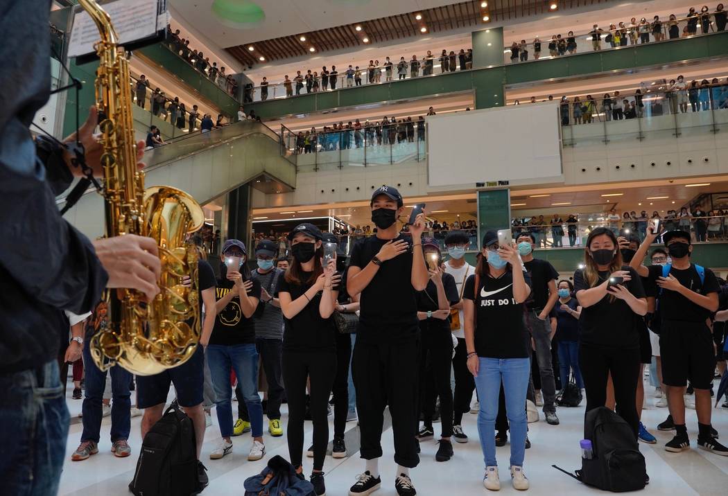 Protestors wearing masks in defiance of a recently imposed ban on face coverings perform at a s ...