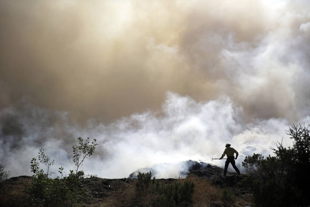 A firefighter works on containment as smoke from a wildfire fills the air Saturday, Oct. 12, 20 ...