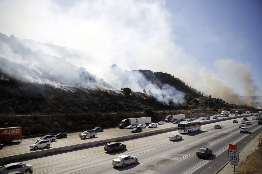 Smoke from a wildfire engulfs a hillside as traffic flows along I-5 Freeway Saturday, Oct. 12, ...