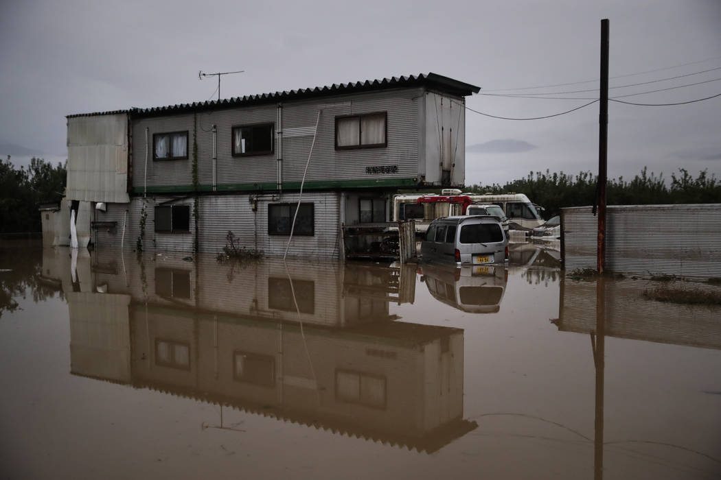 A building is surrounded by floodwaters Monday, Oct. 14, 2019, in Hoyasu, Japan. Rescue crews i ...