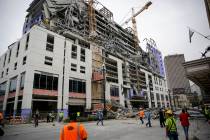 Construction workers look on after a large portion of a hotel under construction suddenly colla ...