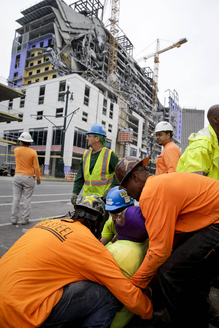 Workers are helped after a large portion of a hotel under construction suddenly collapsed in Ne ...