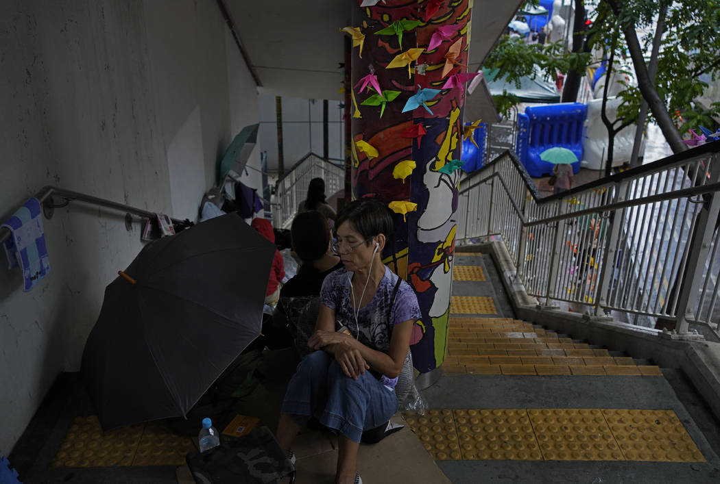 A protester takes a rest during a sit-in outside police headquarters in Hong Kong Monday, Oct. ...