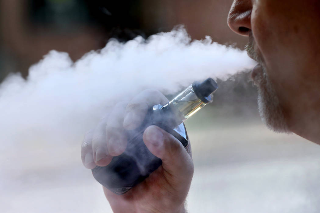 In an Aug. 28, 2019, file photo, a man exhales while smoking an e-cigarette in Portland, Maine. ...
