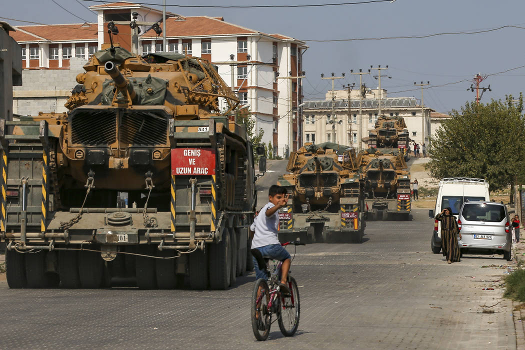 Children watch as army tanks are transported on trucks in the outskirts of the town of Akcakale ...