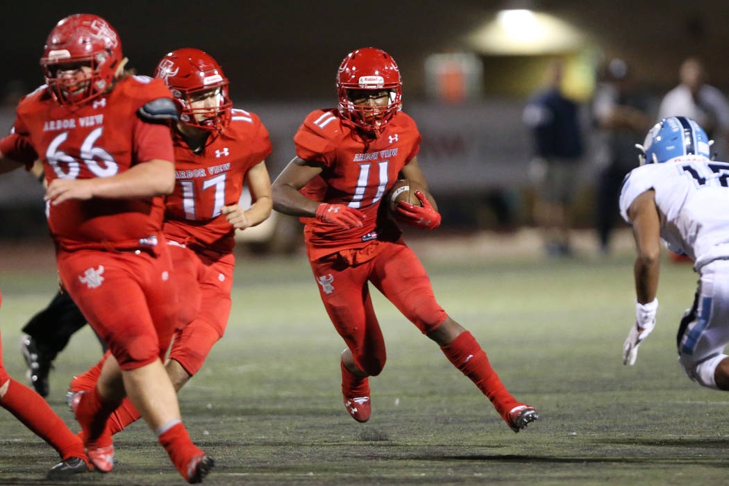 Arbor View's Jaedyn Jackson (11) runs the ball with Kyle Holmes (17) and Gavin Fleming (66) blo ...