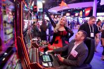 Joyce Jones of Las Vegas shows Maksym Maslii, of Digicode of Plano, Texas, how to play Jackpot ...