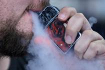 FILE - In this Friday, Oct. 4, 2019 photo, a man using an electronic cigarette exhales in Mayfi ...