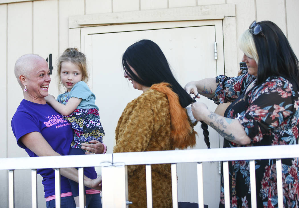 Ronnow Elementary School Principal Michelee Crawford, center, gets her hair cut by Kimberly Mad ...