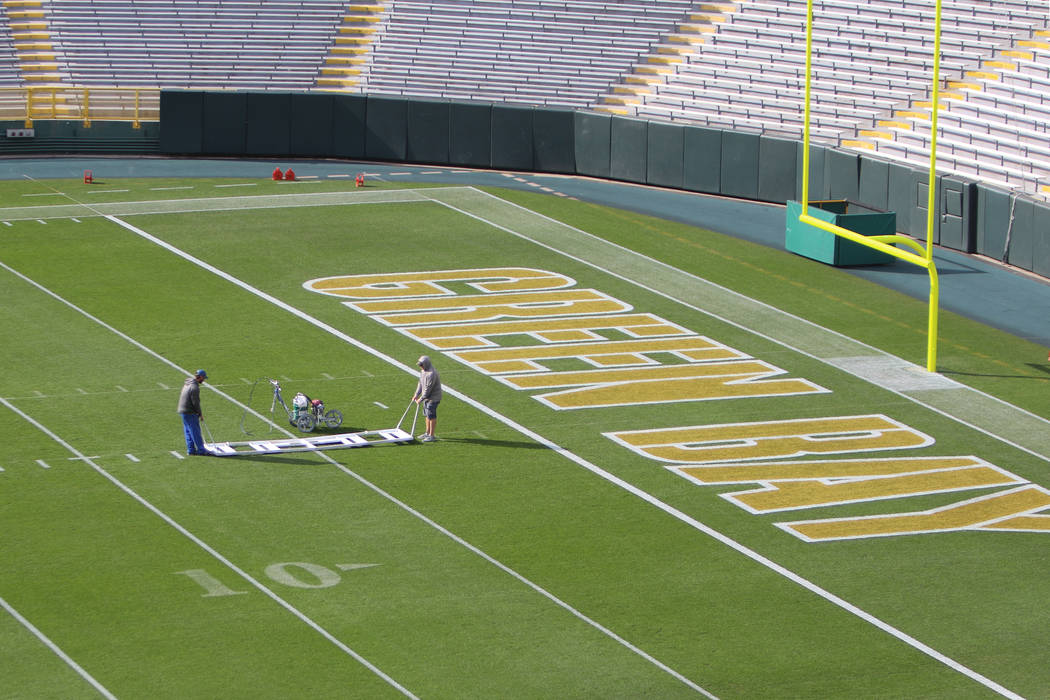 Workers paint hash marks on Lambeau Field in preparation for Sunday's game between the Green Ba ...