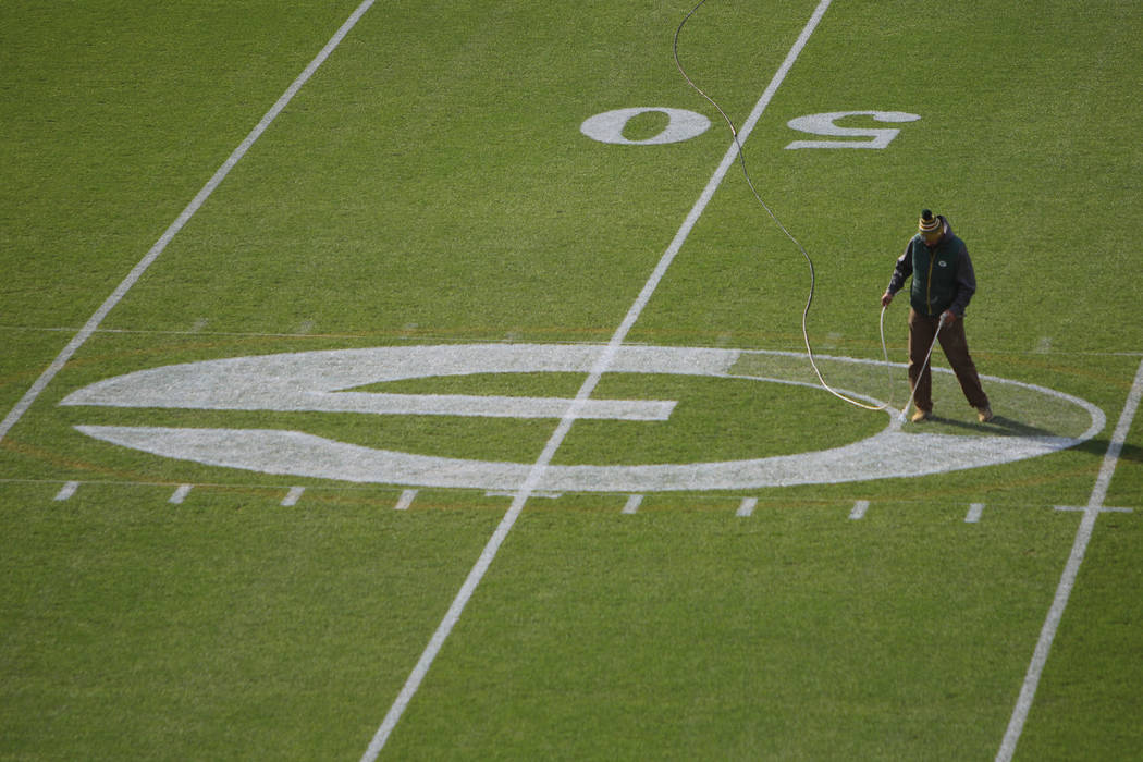 A worker paints the Packer logo at the 50 yard line of Lambeau Field in preparation for Sunday' ...