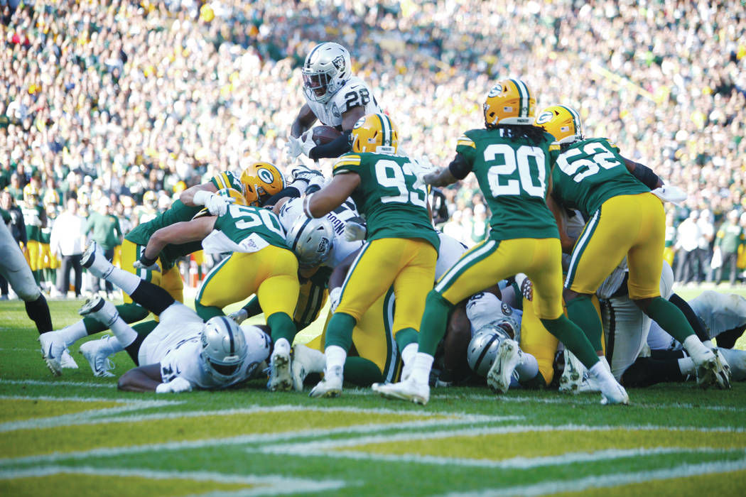 Oakland Raiders running back Josh Jacobs (28) tries to jump over Green Bay Packers' defenders t ...