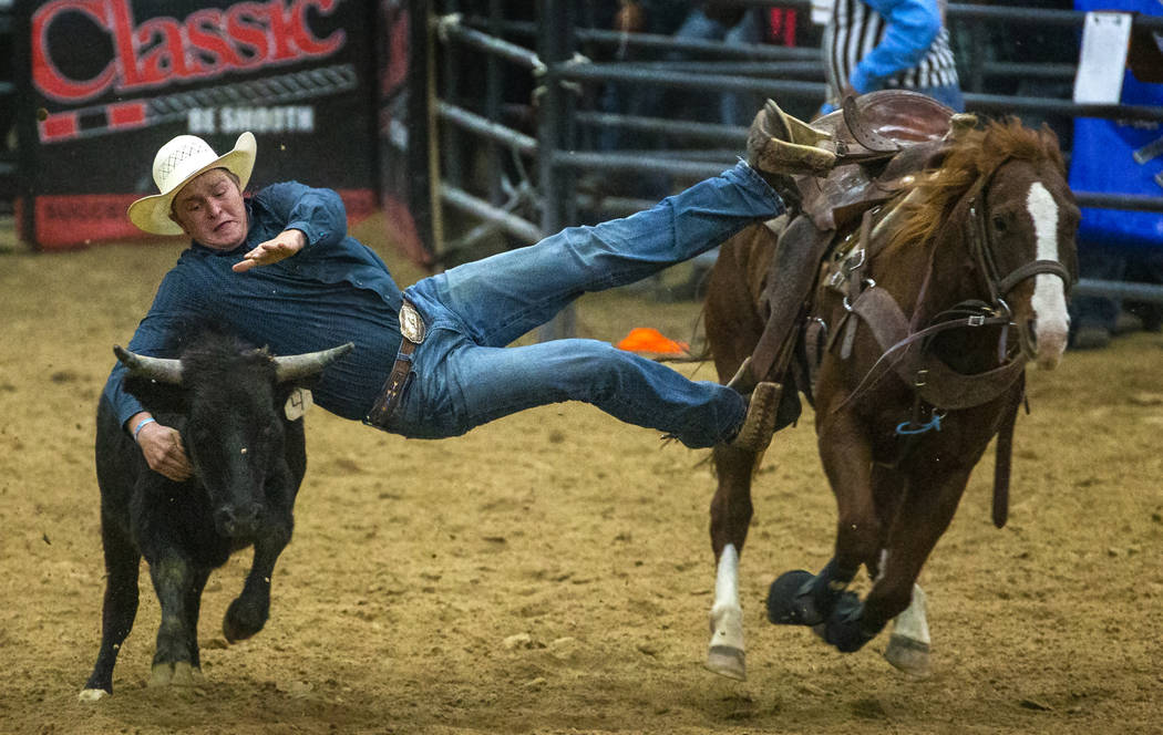 Steer wrestler Tyler Byrne leans way over to grab the steer during the first round of the India ...