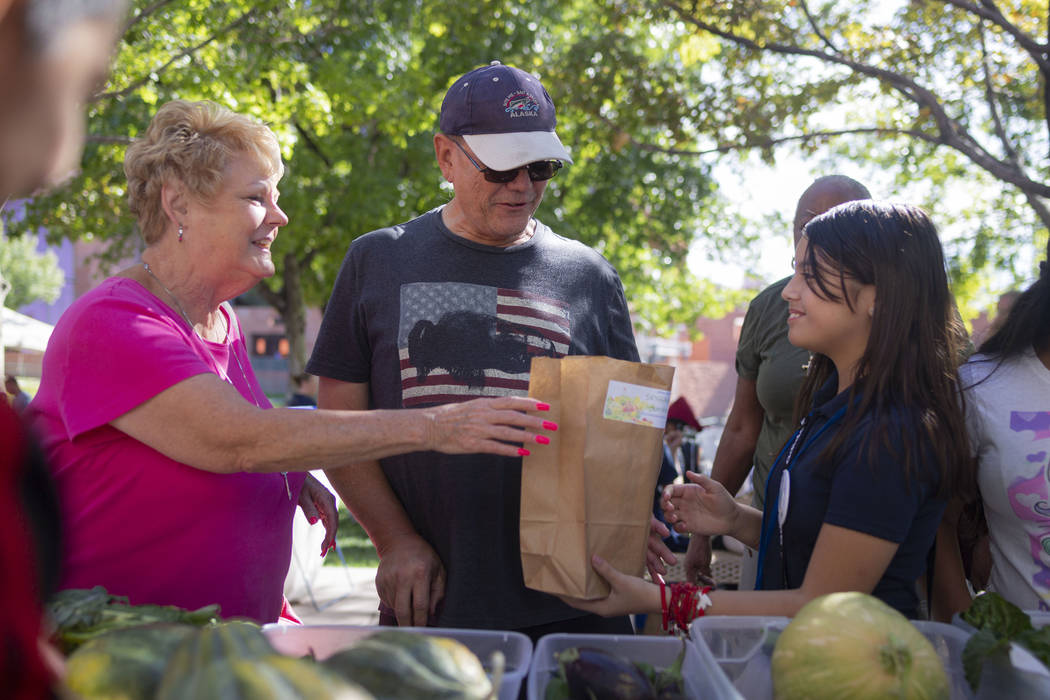 Local Las Vegas residents Cindy Smith, left, and Jeff Smith, center, purchase produce from Hele ...