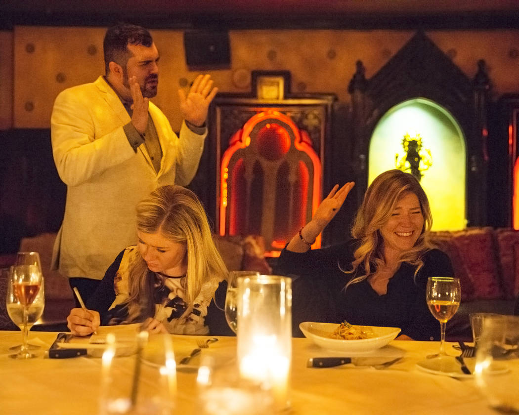 Psychic medium Thomas John, left, provides readings to guests during Dinner with the Dead on Fr ...