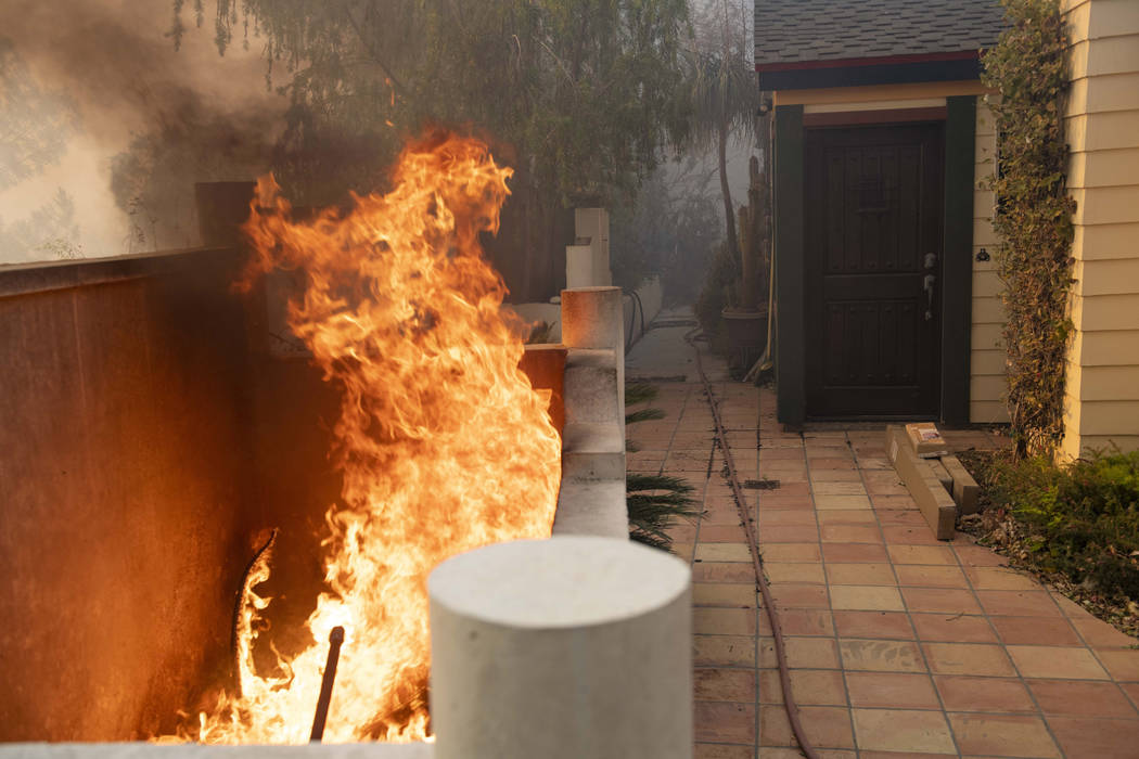Flames burn close to an entrance of a home during the Tick Fire in Santa Clarita, Calif., on Th ...