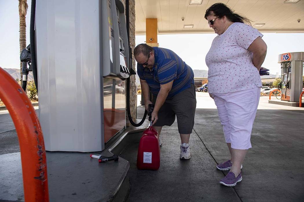 Richard and Sheri Rose fill a plastic jerry can to power their generator while the power remain ...