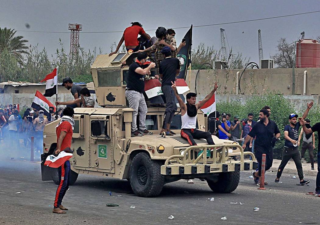 Protesters ride an Iraqi Army armored vehicle during a demonstration in Basra, Iraq, Friday, Oc ...