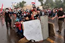 Anti-government protesters take cover while Iraq security forces fire during a demonstration in ...