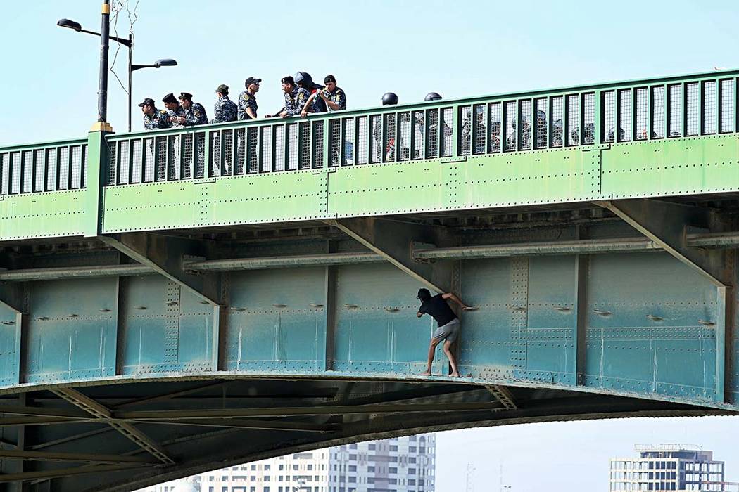 An anti-government protester tries to sneak while Iraqi security forces close the bridge leadin ...