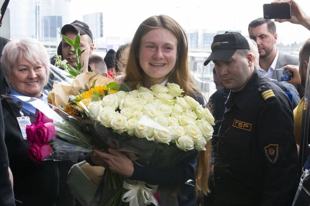 Russian agent Maria Butina, center, holds a bunch of flowers upon her arrival from the United S ...