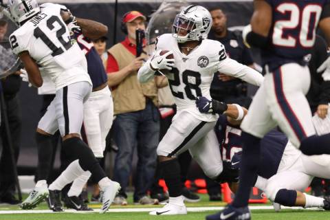 Oakland Raiders running back Josh Jacobs (28) tries to shed a tackle from Houston Texans outsid ...