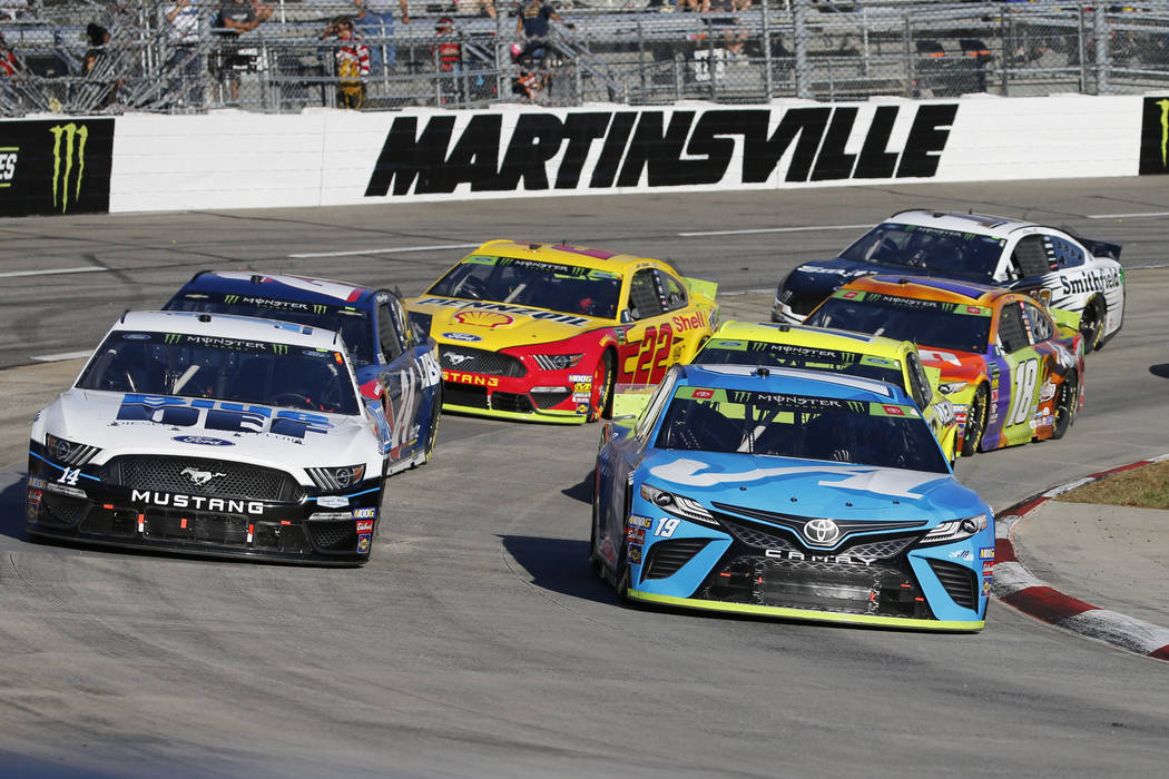 Martin Truex Jr. (19) and Clint Bowyer (14) lead the field in turn four during a restart of the ...