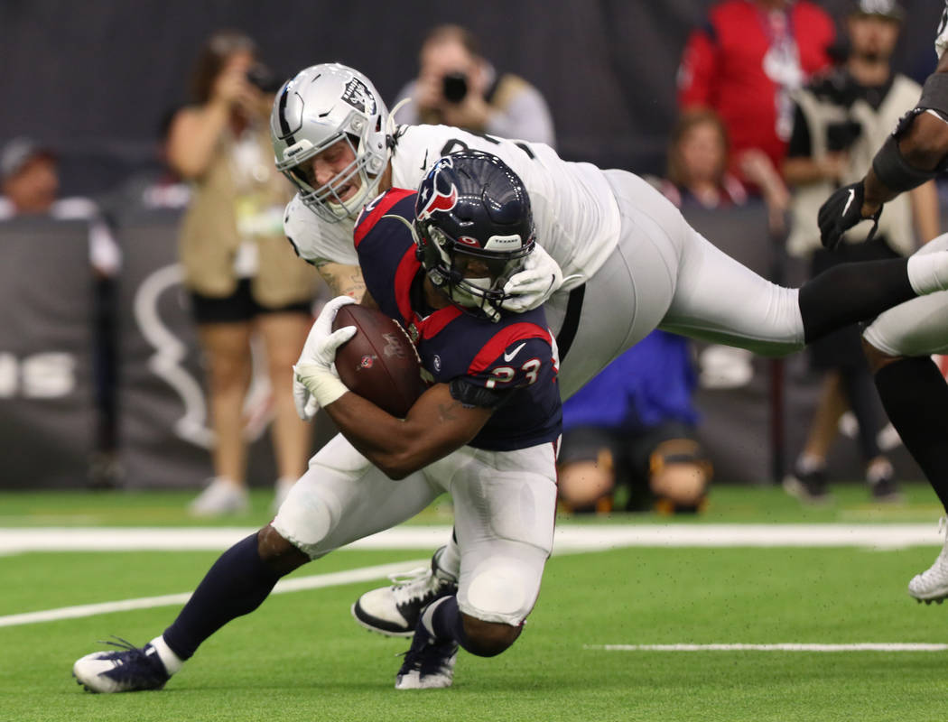 Oakland Raiders defensive end Maxx Crosby (98) grabs the facemask of Houston Texans running bac ...